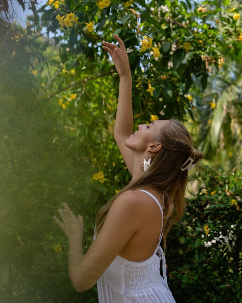 melissa streckt sich im Garten nach gelben Blüten