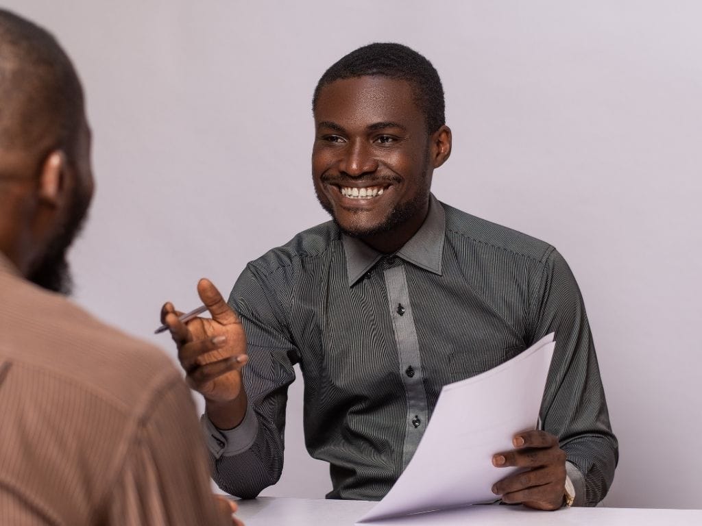 Two men from a delivery organisation, one completing an impact survey to record beneficiary outcomes in real time