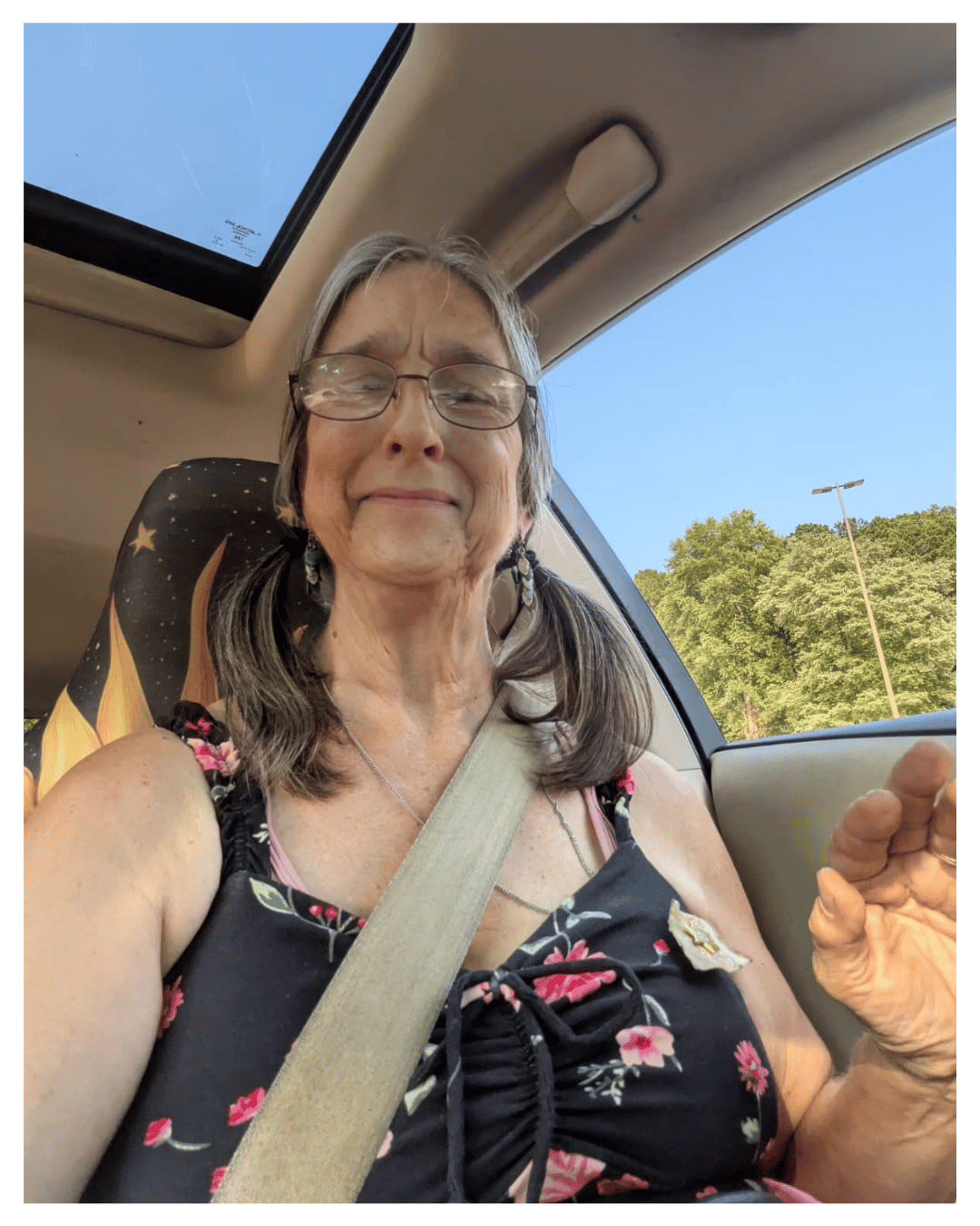 Cynthia Lees taking a selfie in her car while raising her hand, sharing a personal moment from her journey as an author and Light practitioner.
