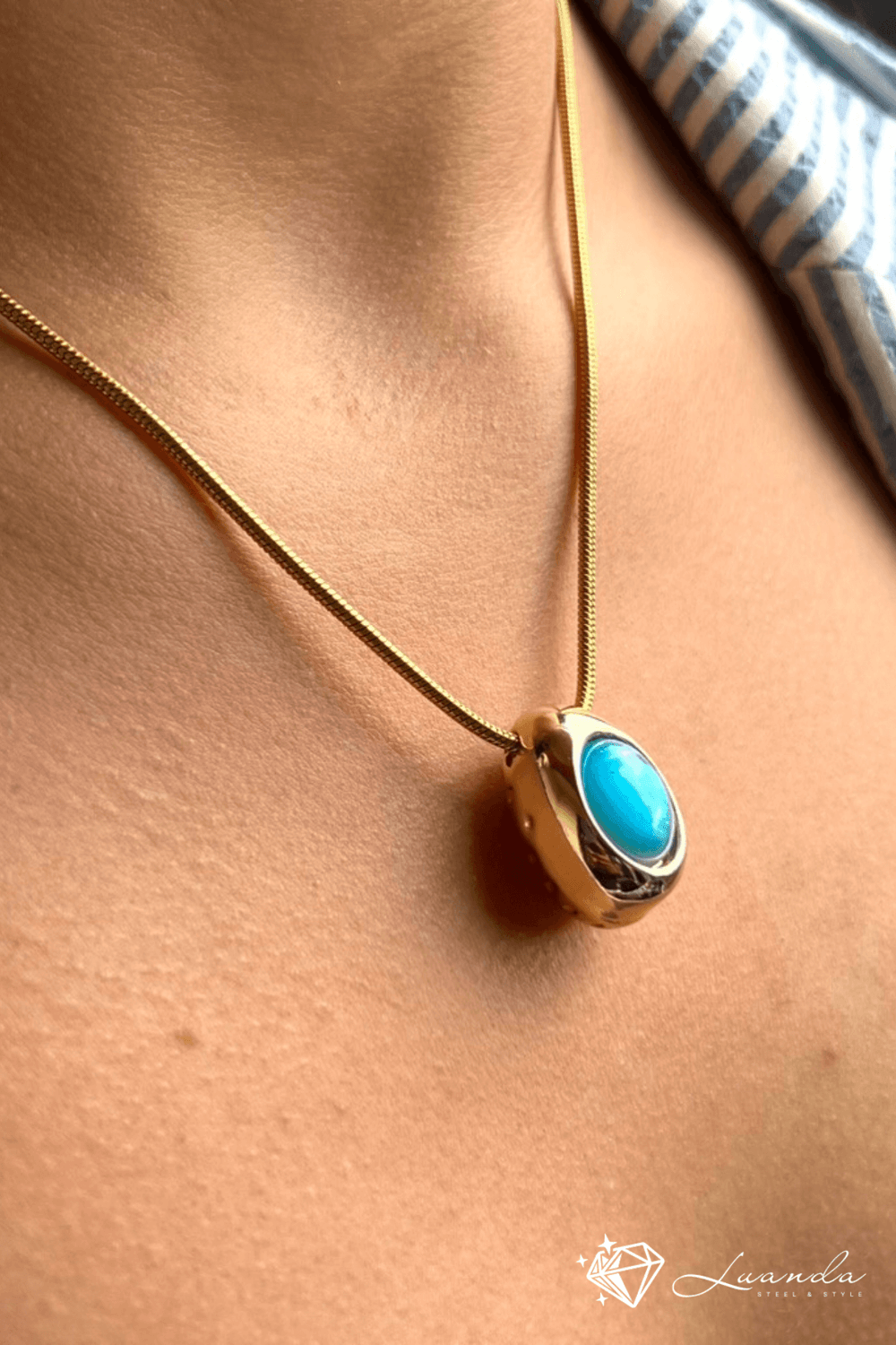 Collier en acier inoxydable plaqué or avec pendentif ovale et pierre turquoise, porté autour du cou – Luanda Steel & Style
