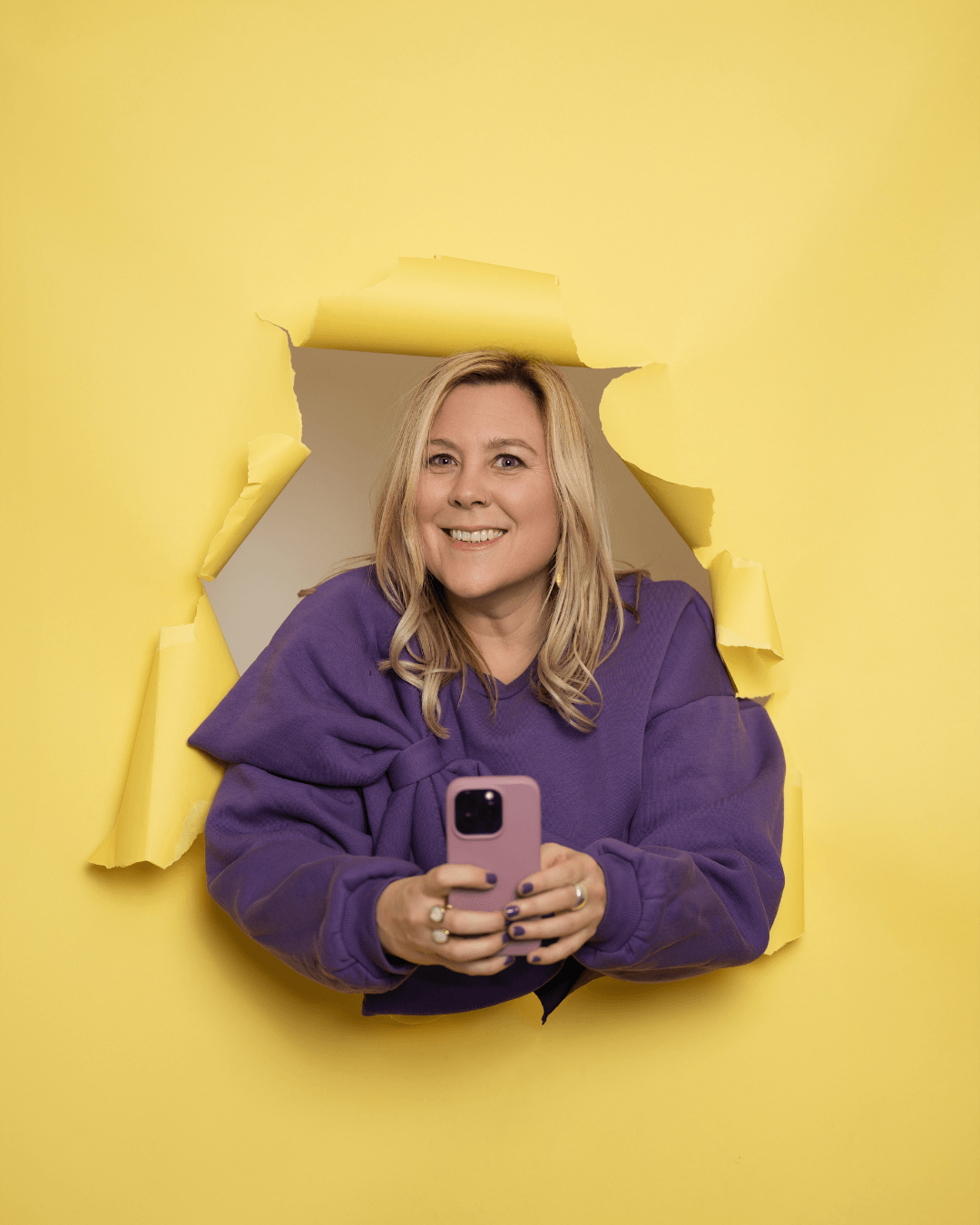 Sophie Le Millour filme une vidéo avec son téléphone, sur fond jaune