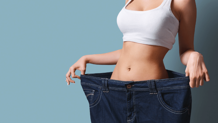 Femme montrant le résultat d'une perte de poids avec son jean trop grand, illustrant le succès du Régime Cétogène et la réponse à : Combien de temps pour maigrir ?