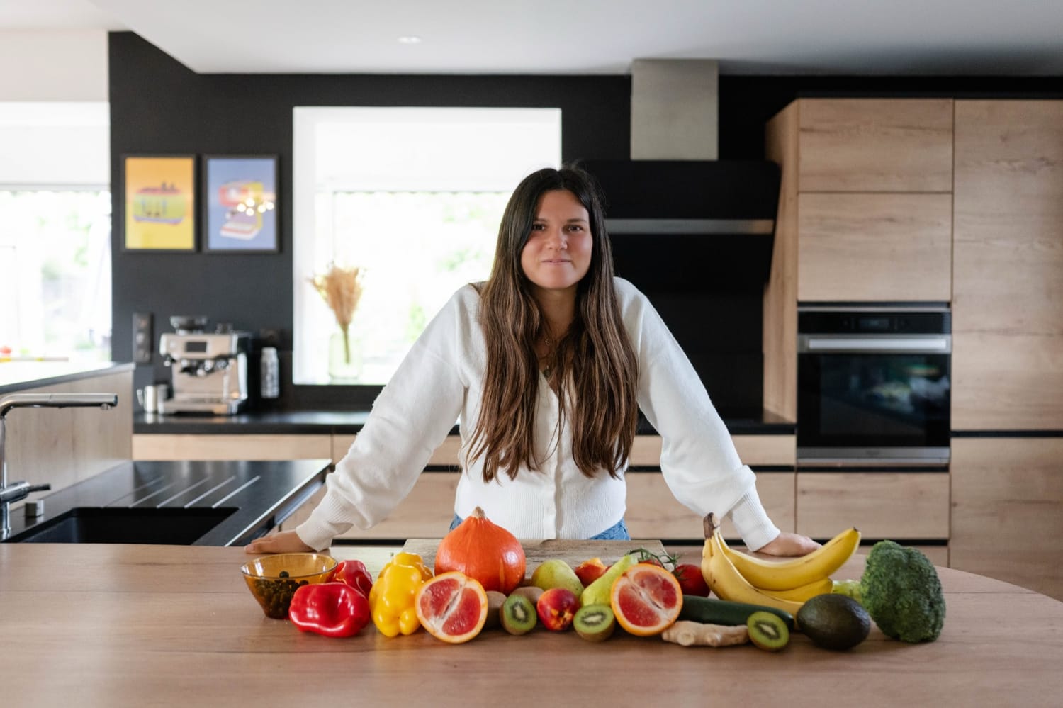 Mélanie Padovani dans sa cuisine, derrière un plan de travail couvert de fruits et légumes de saison