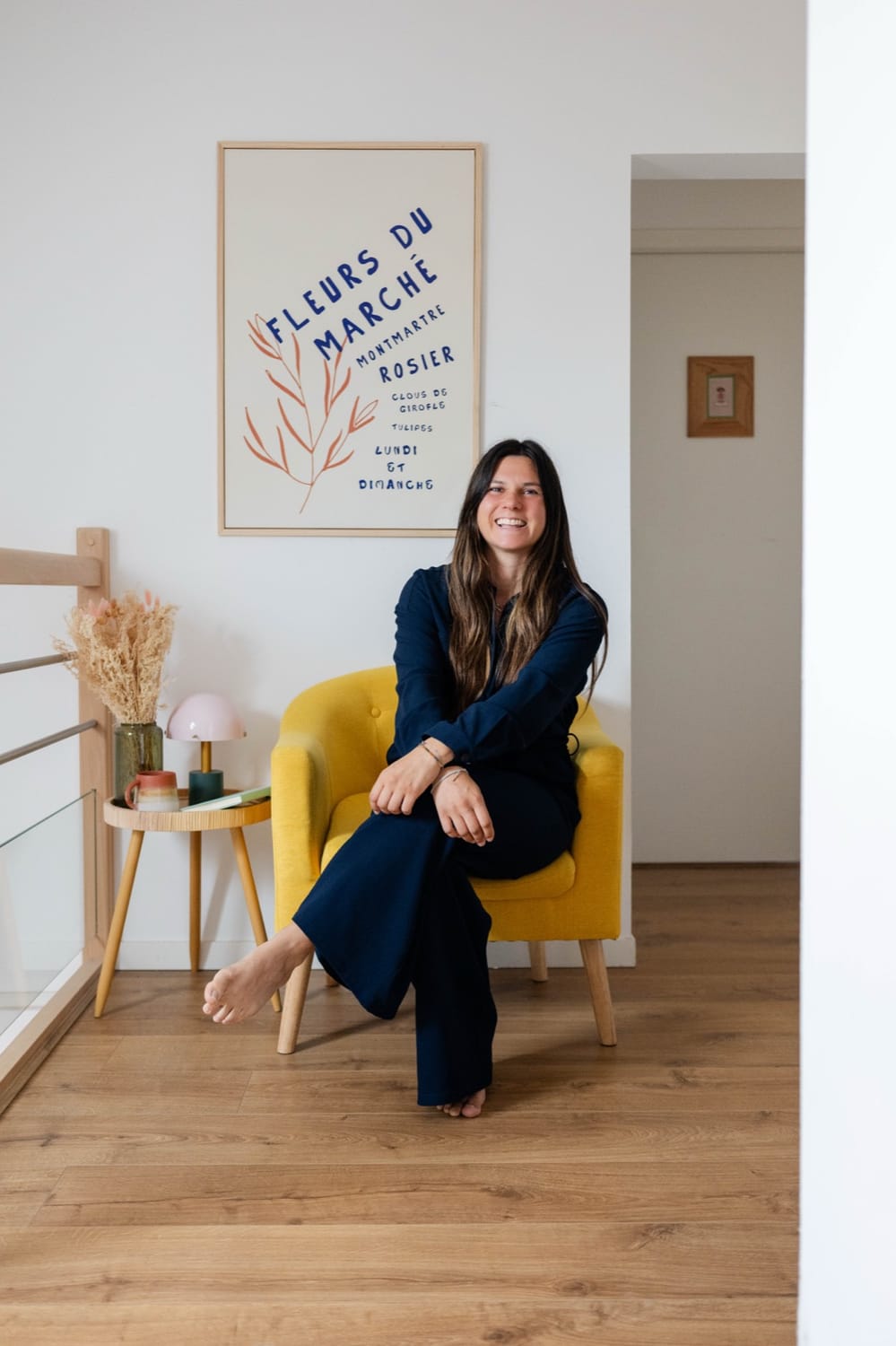 Mélanie Padovani assise dans un fauteuil jaune dans son salon
