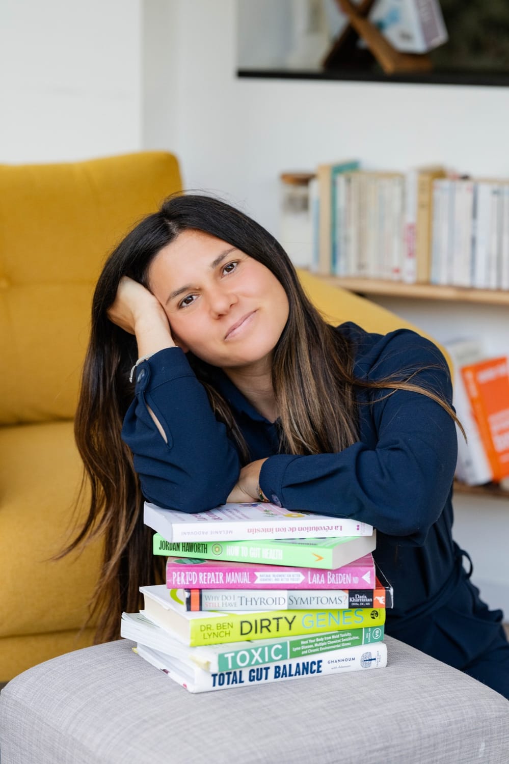 Mélanie Padovani, la joue posée sur une pile de livres sur la santé intestinale