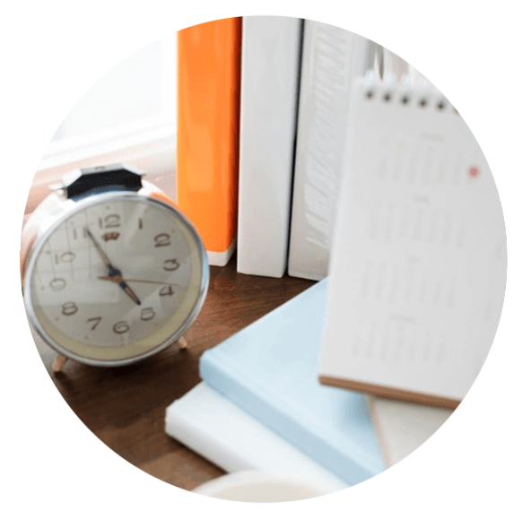"Réveil posé sur un bureau avec des livres et un calendrier"