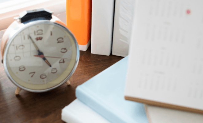 "Réveil posé sur un bureau avec des livres et un calendrier"