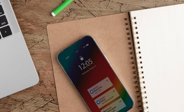 "Smartphone posé sur un carnet avec stylo et plante en arrière-plan"