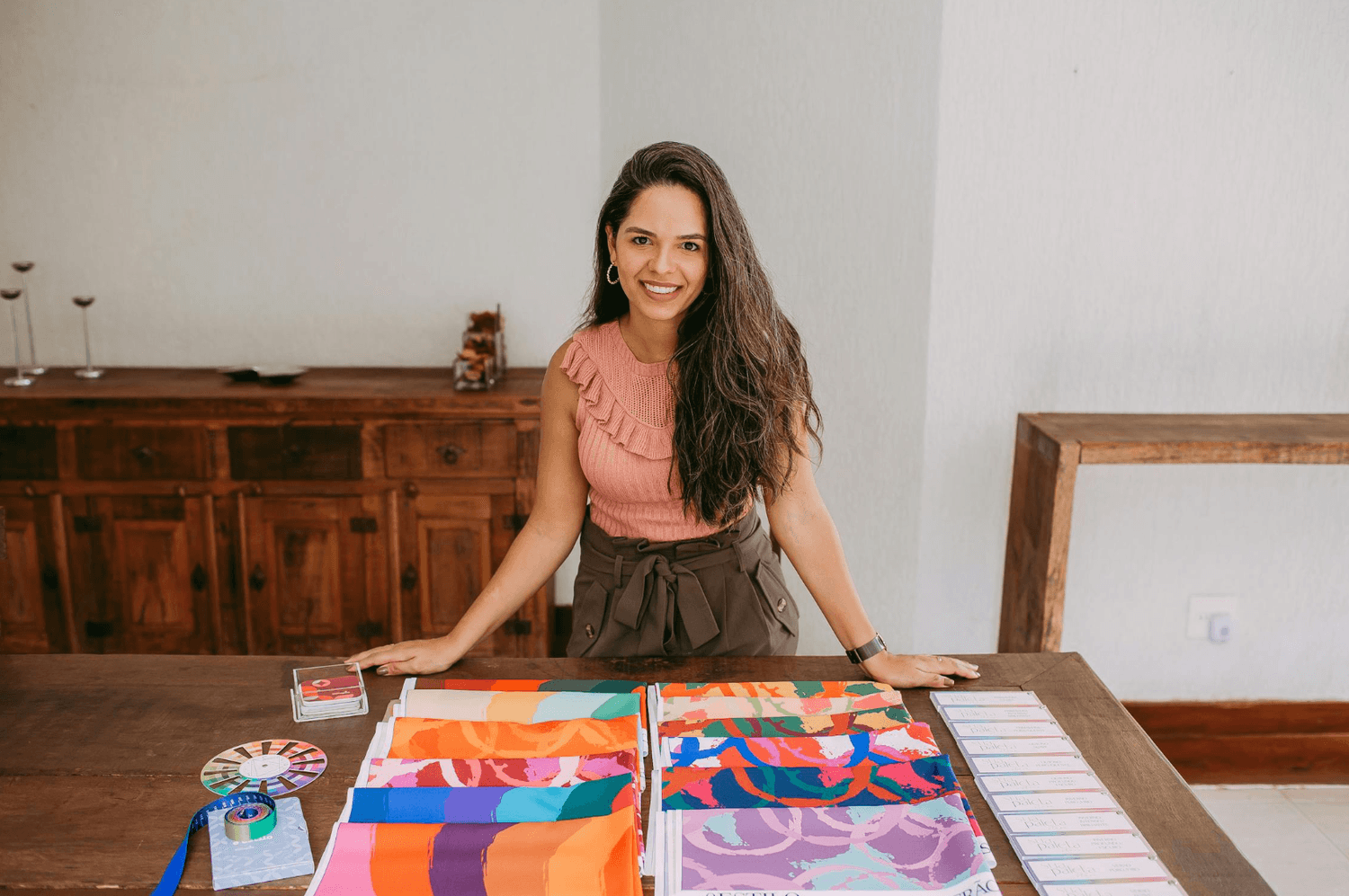 alt="Créatrice indépendante présentant fièrement ses collections et ses outils de travail dans son atelier"