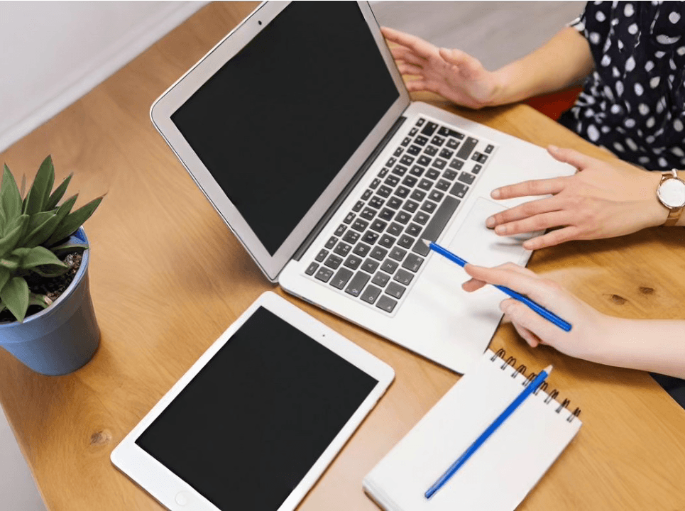 alt="Un homme debout prend la parole devant quatre participants à atelier assis autour d'une table blanche dans un bureau moderne et lumineux décoré de plantes"