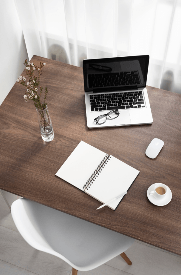 "Vue d'en haut d'un bureau en bois foncé avec un ordinateur portable ouvert, un carnet de notes et une tasse de café "