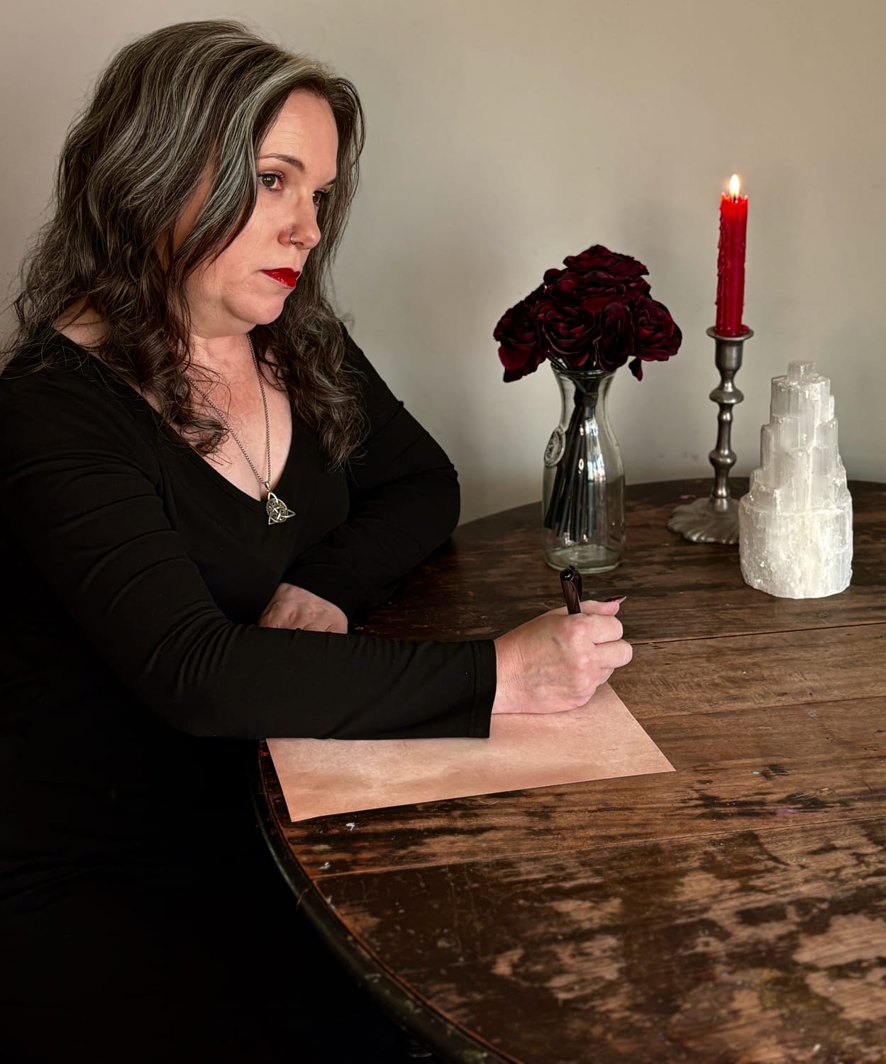 Woman writing letters from altar with candles and herbs