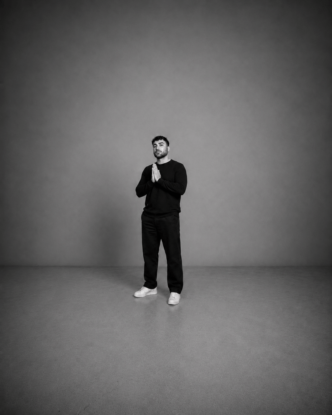 Kadir Demir im Studio stehend mit gefalteten Händen