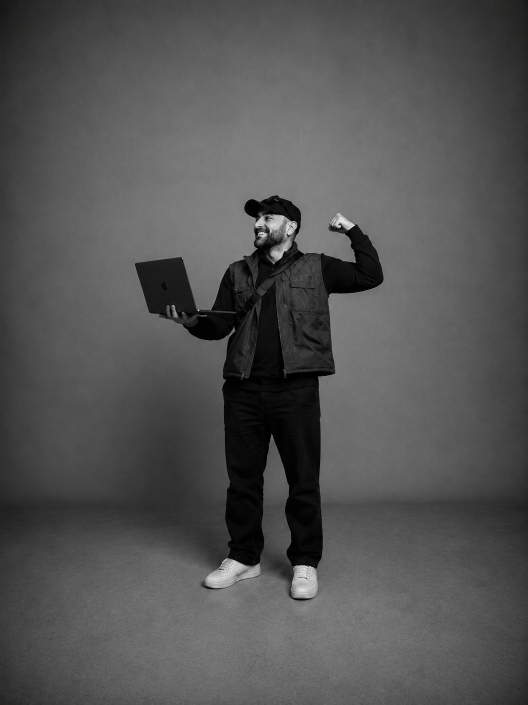 Kadir Demir im Studio mit Laptop und erhobener Hand