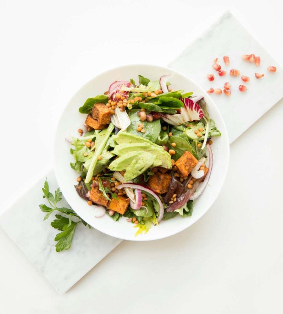 Raw Reset salad bowl with dehydrated sweet potato, avocado and pomegranate seeds.