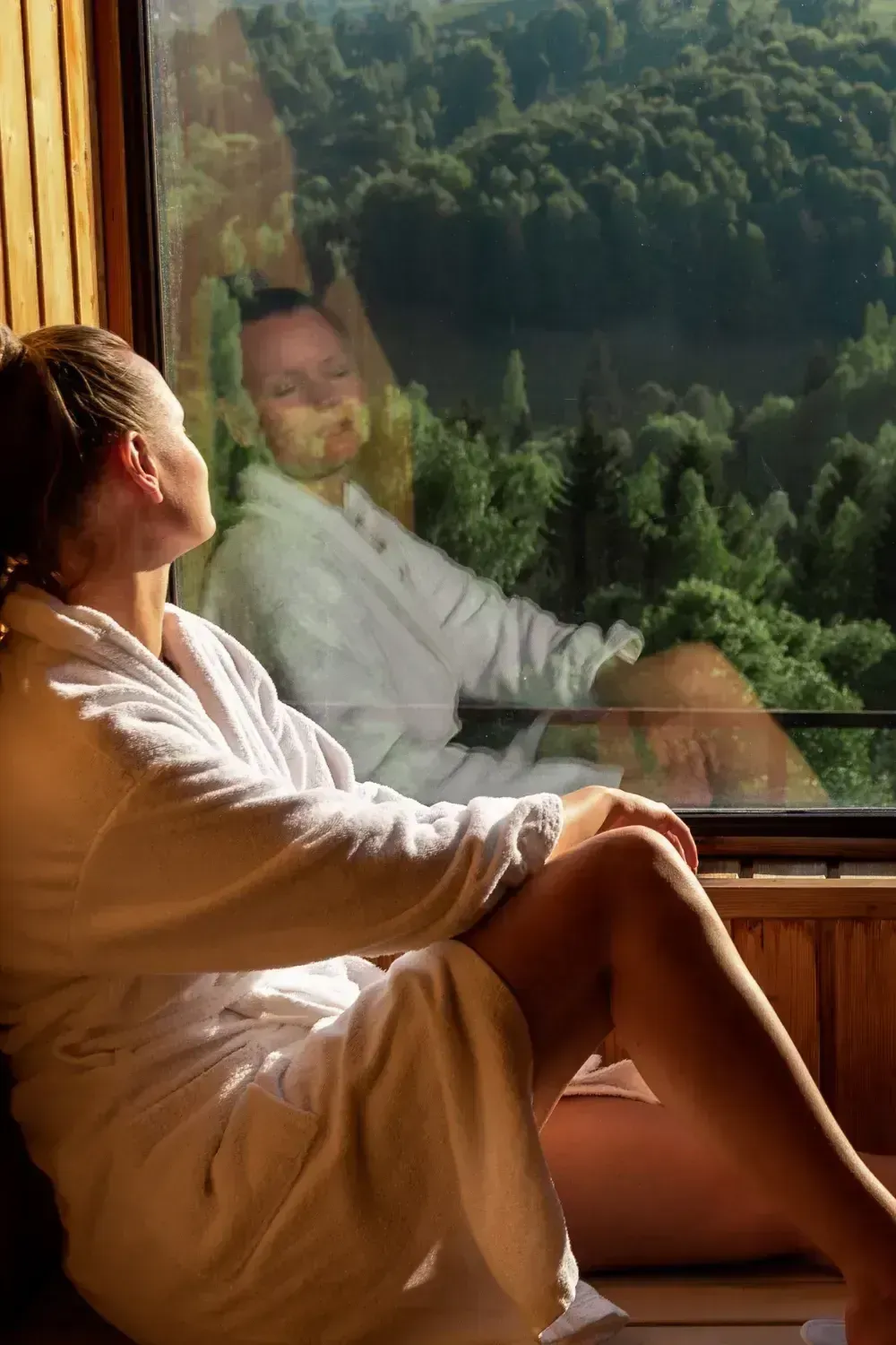 Person sitting by a window with phone face-down, looking outside during a digital detox challenge
