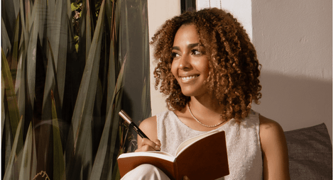 Femme qui écrit en souriant.
