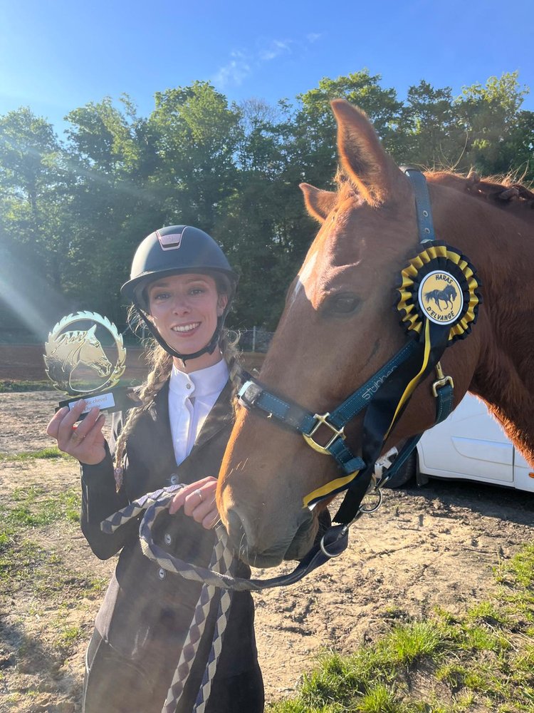 Camille avec son cheval et un trophée de concours