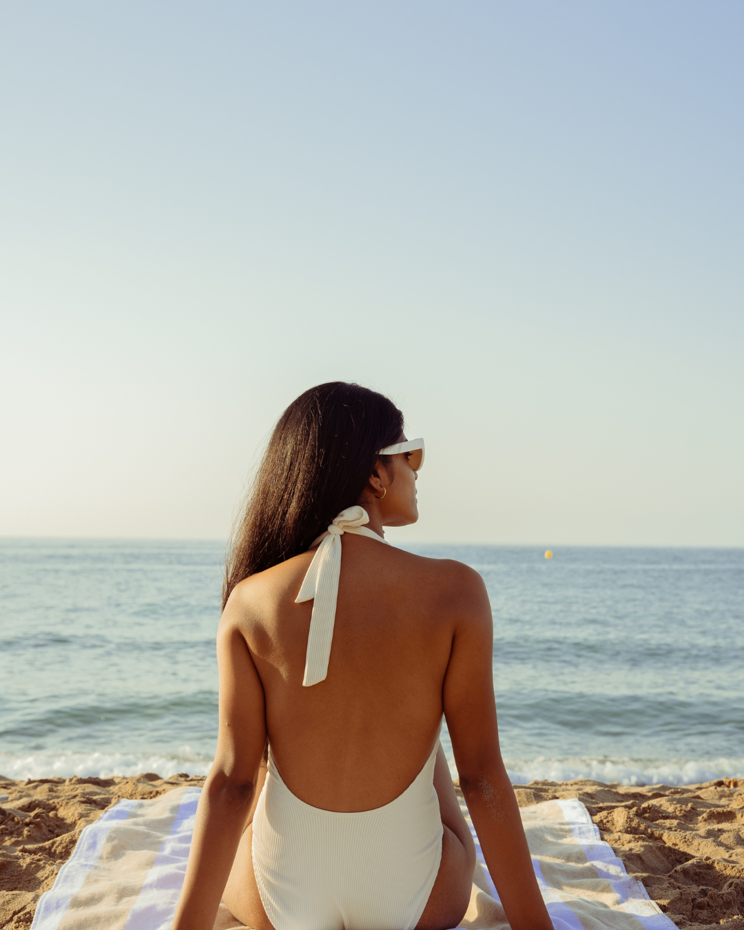 Eine Frau mit langen, lockigen Haaren trägt einen schwarzen Glitzerblazer und ein bordeauxrotes Shirt. Sie jubelt voller Energie mit ausgestrecktem Arm und zeigt nach oben, während Konfetti um sie herum fliegt. Ihr Gesichtsausdruck ist ausgelassen und freudig. 