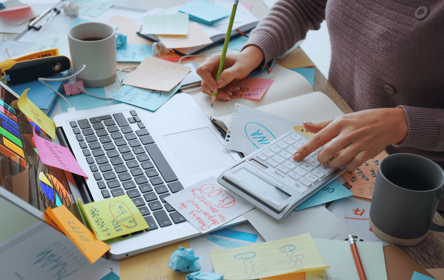 A cluttered desk covered in sticky notes representing entrepreneur overwhelm and mental load.