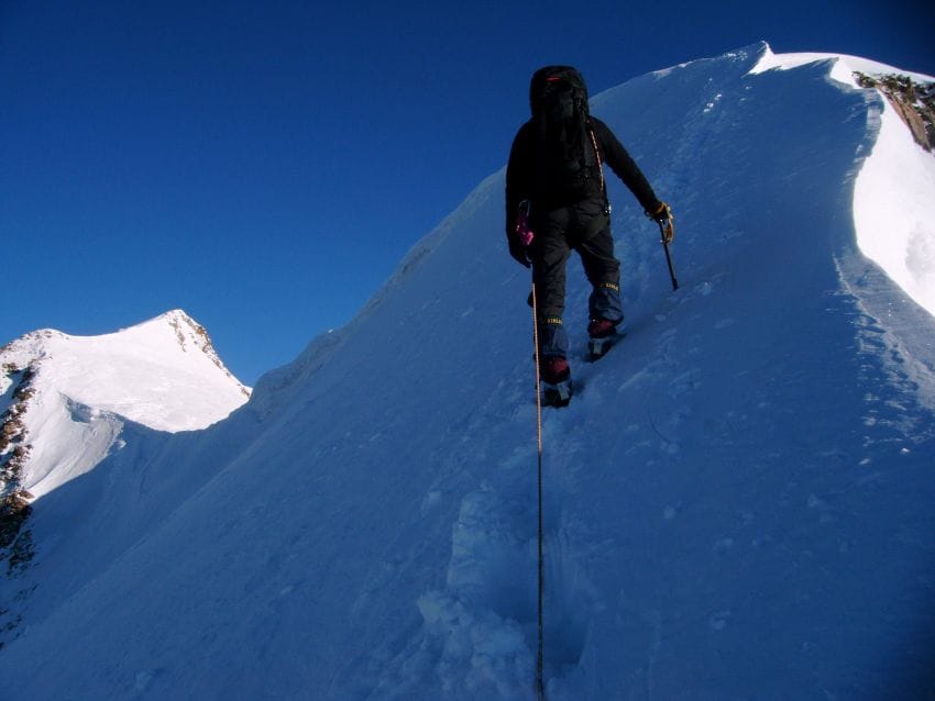Escalador progresando por una fuerte pendiente nevada con máxima concentración, representando el enfoque total necesario para evitar el bloqueo mental y resolver problemas de uno en uno.