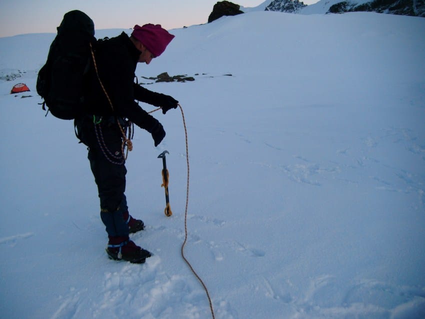 Un alpinista en un glaciar comprueba meticulosamente la cuerda de seguridad con total enfoque, ejemplificando cómo centrarse en una sola cosa ayuda a bajar el ruido mental, como se menciona en el punto 4.
