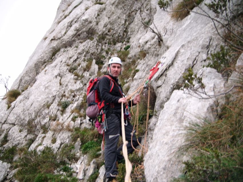 Montañero parado en reunión de escalada representando el cuerpo en alerta y la tensión sostenida