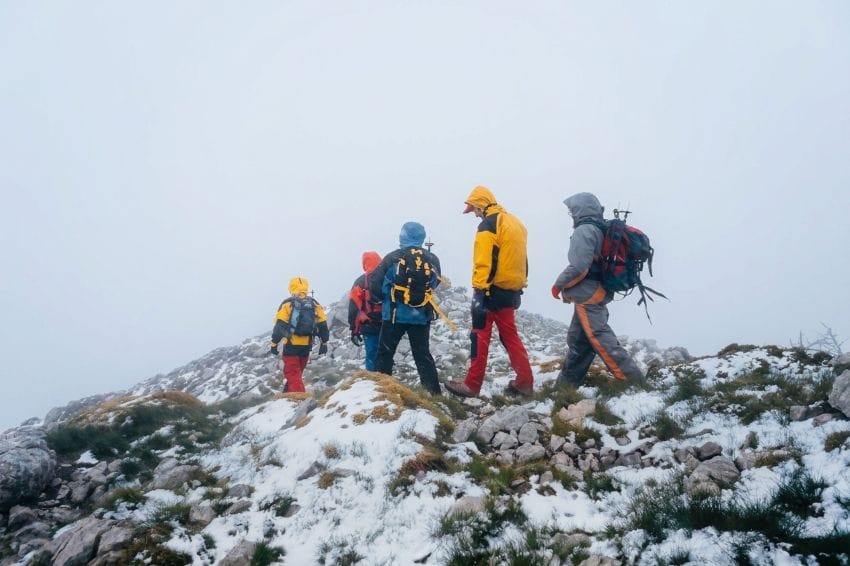 Grupo de senderistas caminando en una montaña con niebla densa, reflejando la saturación mental antes de tomar decisiones importantes.