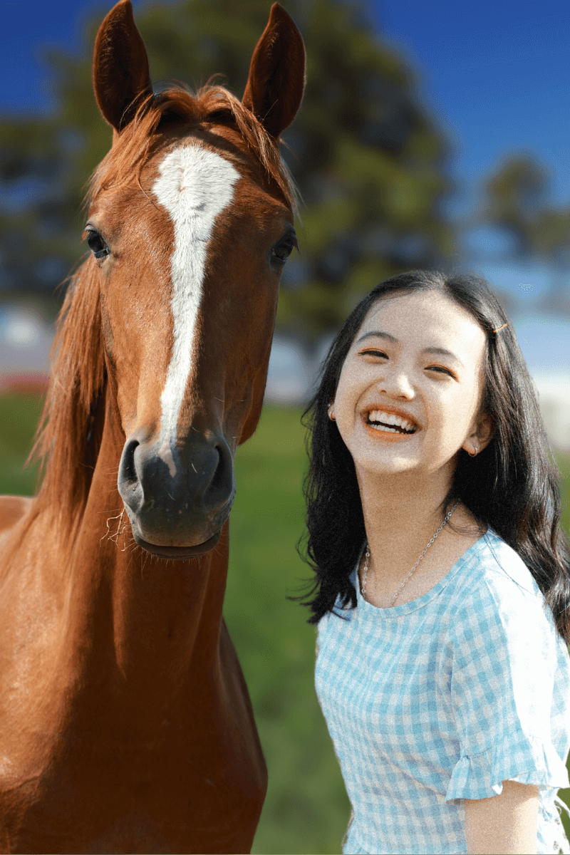 Smiling teen girl standing beside a chestnut horse during a Spirited Hooves confidence-building session outdoors