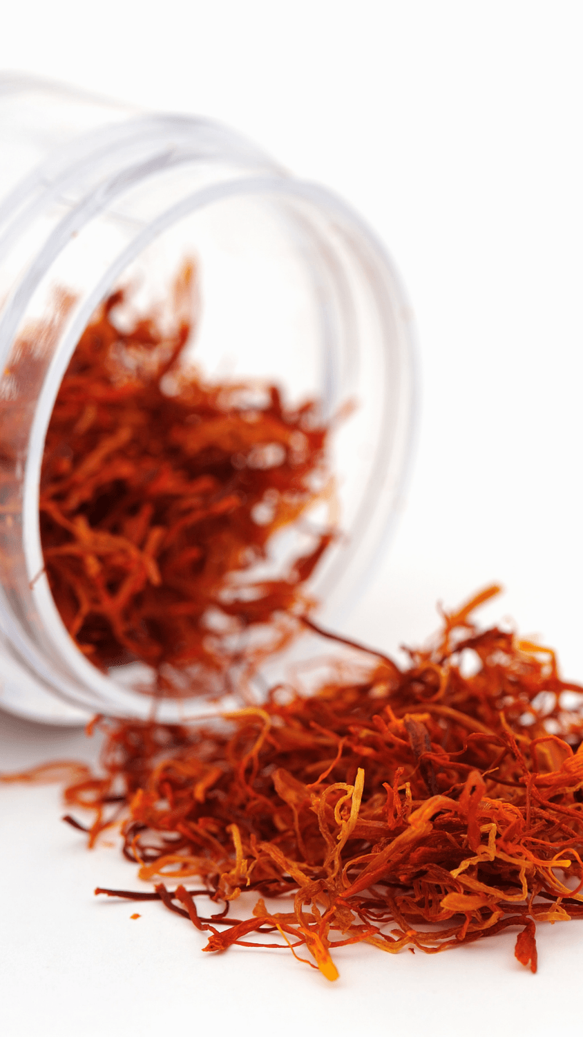 Läpinäkyvä purkki, josta on kaadettu ulos kuivattuja säikeitä valkoiselle pinnalle.