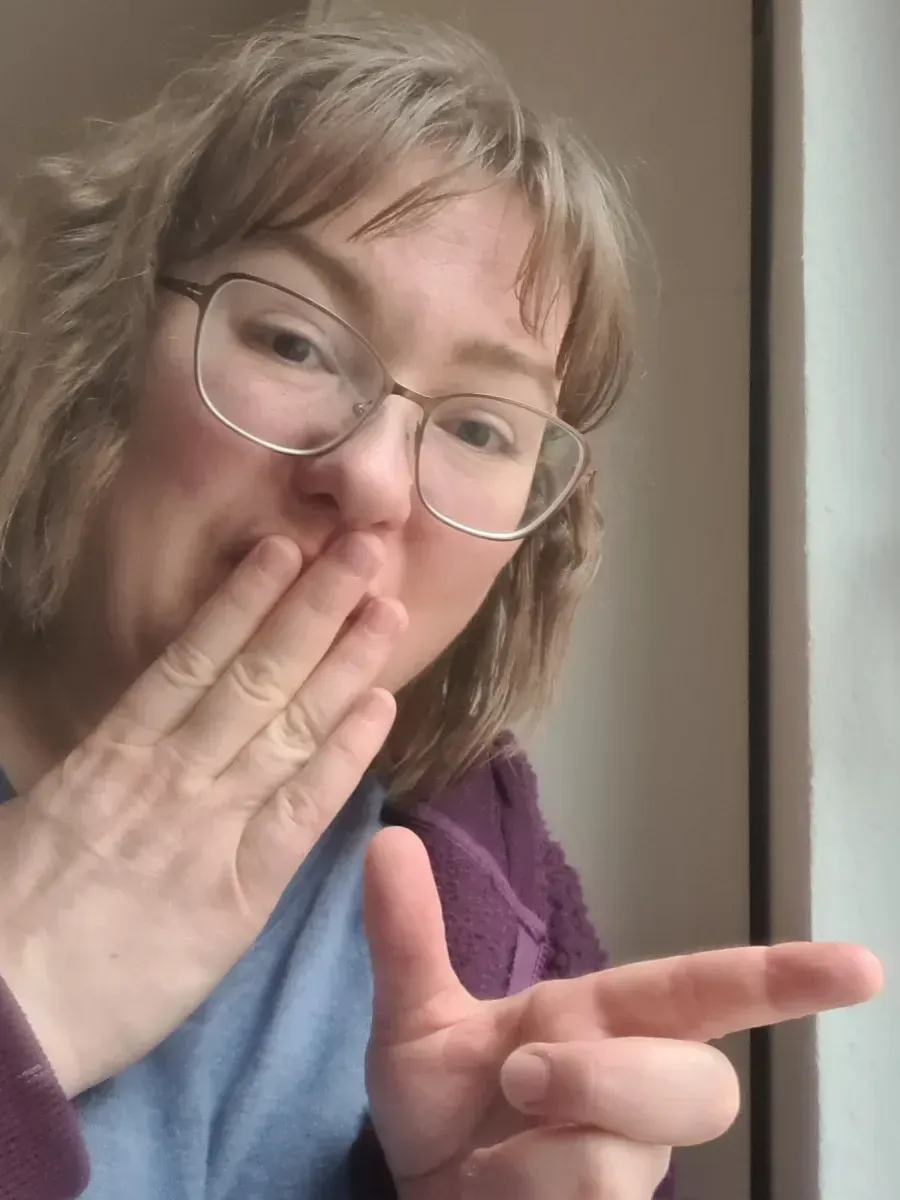 Frau mit lockigen Haaren im Glitzerblazer jubelt mit ausgestrecktem Arm, umgeben von Konfetti.