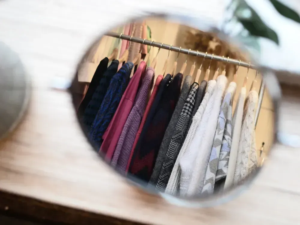 Nahaufnahme Sonnenbrille mit Spiegelung von Kleiderstange mit sortierter Bekleidung