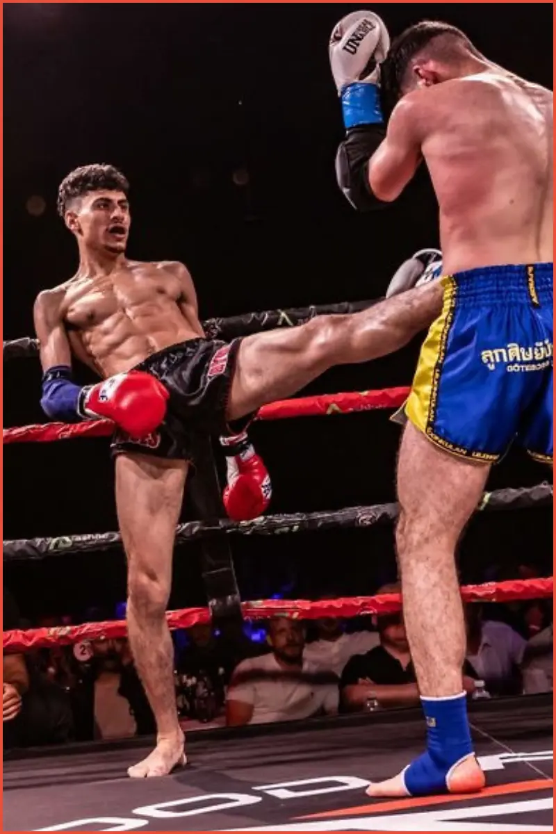 Mo Khalifa in a boxing ring, kicking his opponent with a front kick (Teep) to his sternum. Ouch!