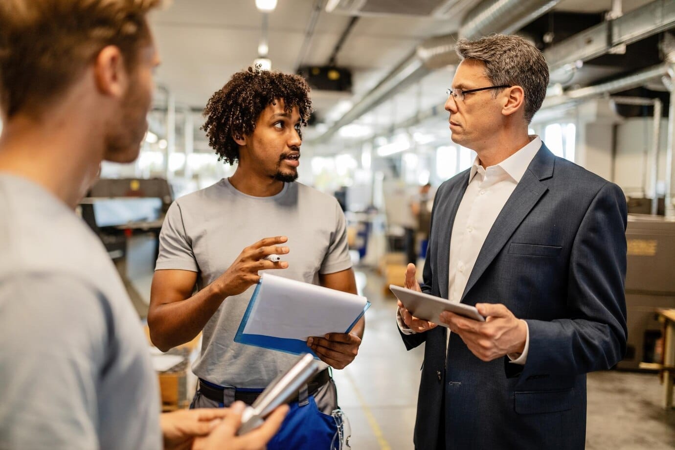 mid-adult-engineer-using-touchpad-communicating-with-african-american-worker-about-product-reports-industrial-building_637285-4098.jpg