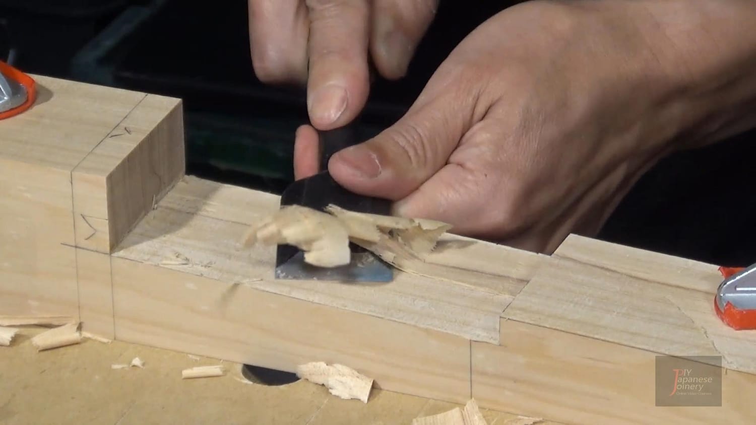 Japanese chisel slicing a thin, clean shaving from a piece of wood