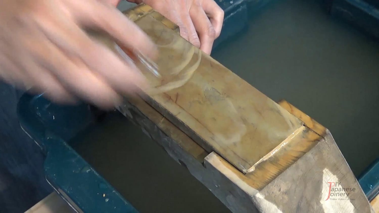 A Nagura stone being rubbed on the surface of the finishing stone, producing slurry.