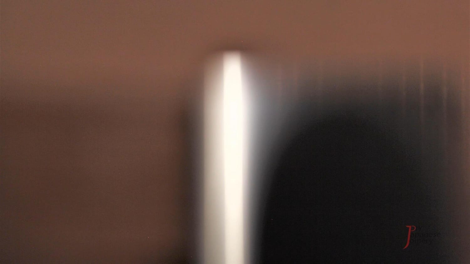 A chisel backside reflecting a fluorescent light tube straightly, showing flatness.