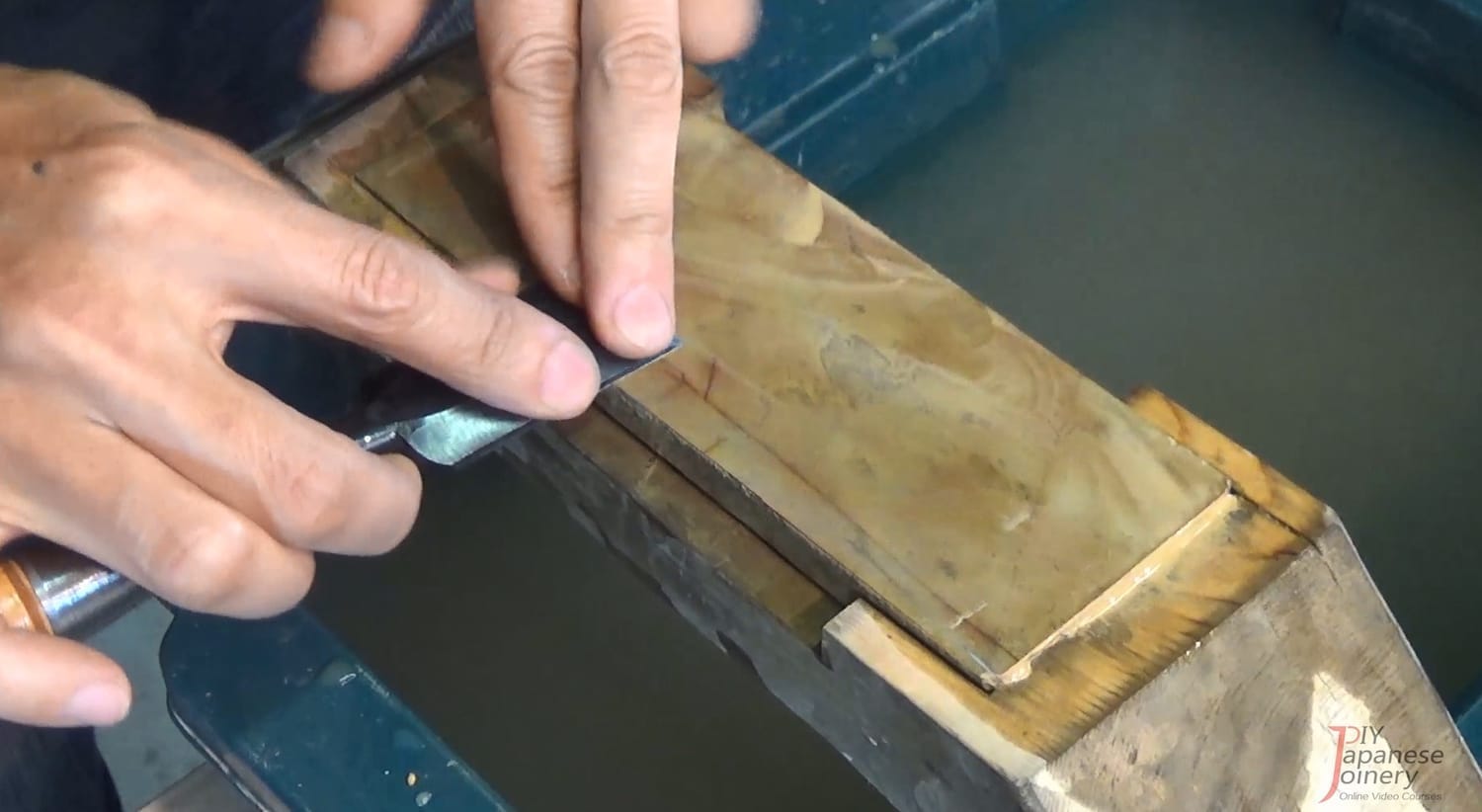 Action photo of polishing the backside of a chisel on a finishing stone.