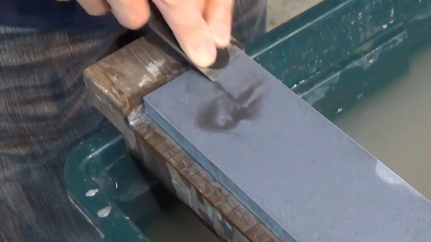 Starting to sharpen the chisel with strokes about 30 mm long from the near end of the stone.