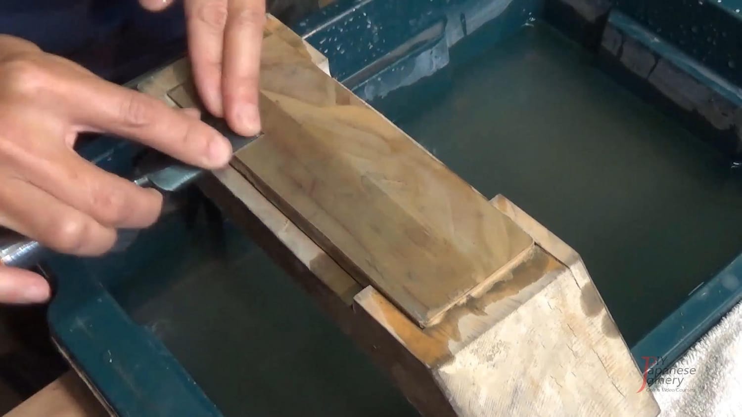 Close-up of the backside of a chisel being polished on a finishing stone.