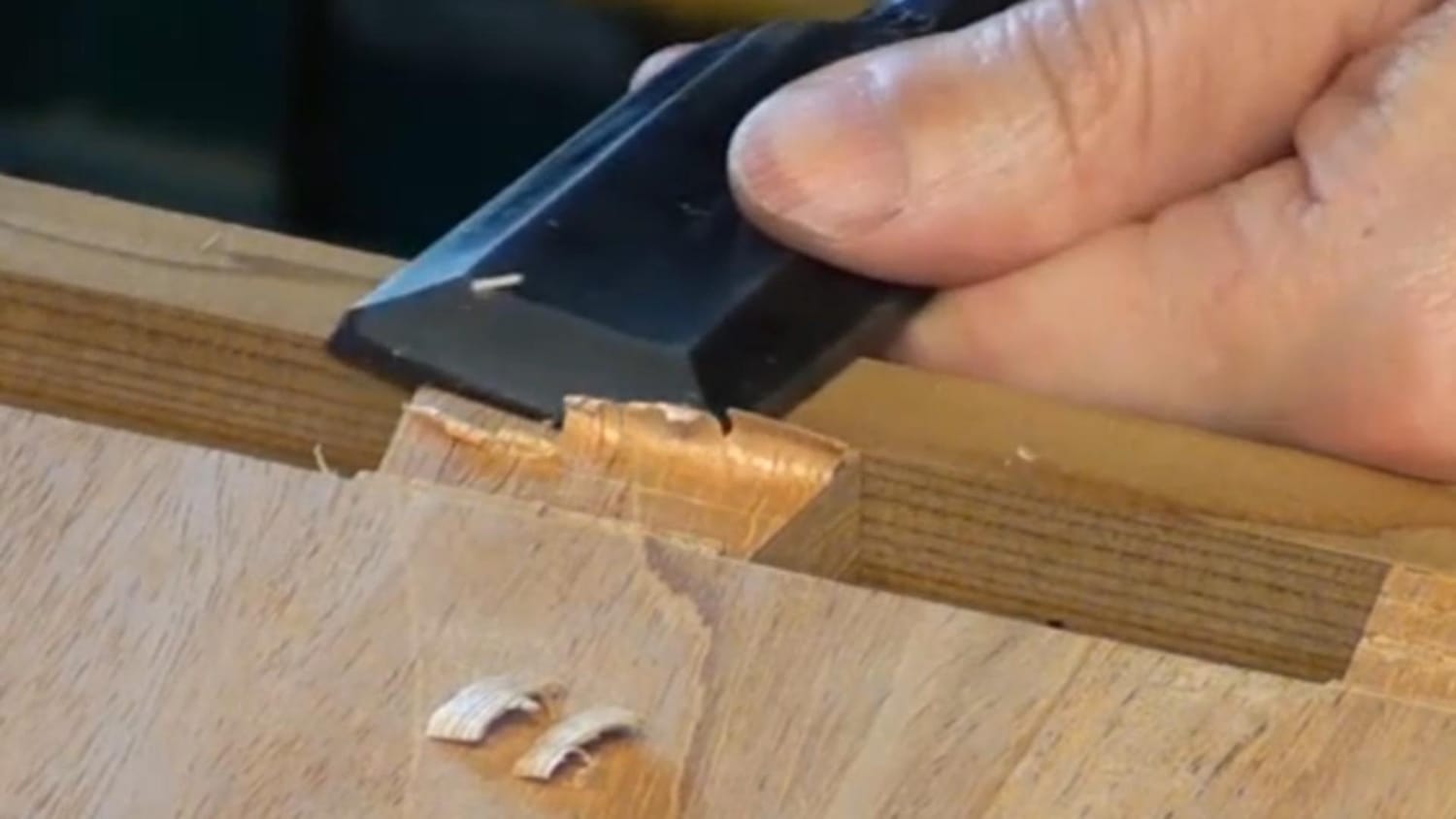 Woodworker using a chisel on end grain, listening for sound changes as the blade dulls.