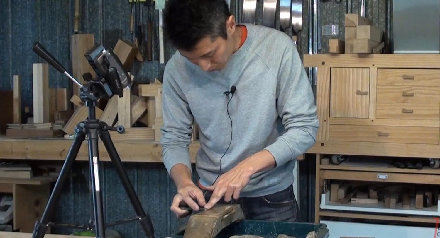 Craftsman sharpening a Japanese plane blade on a whetstone, water reflecting the edge.