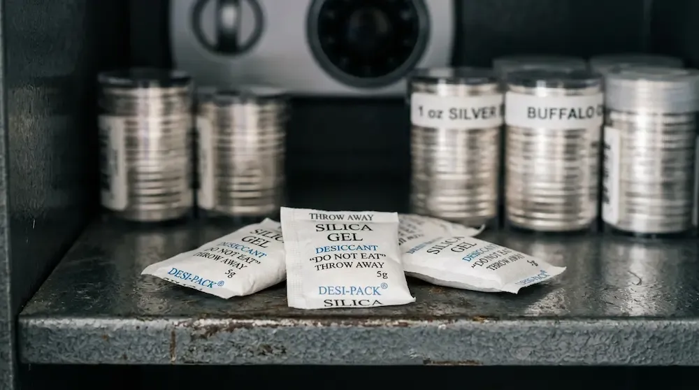 Silica gel desiccant packs placed next to silver coin tubes inside a safe to prevent humidity and moisture tarnish.