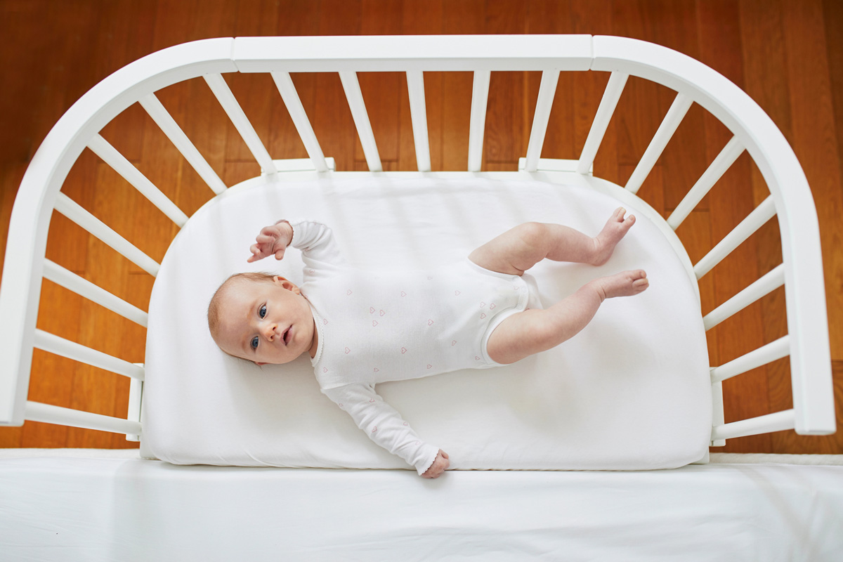 Baby Six Month Sleep Regression Guide - baby laying on back and smiling
