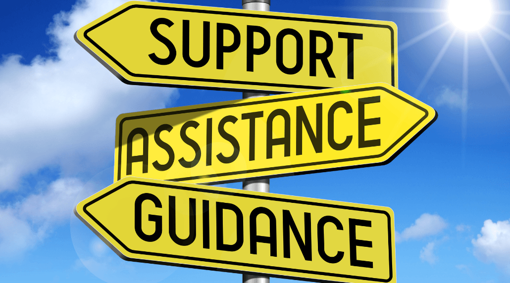 'Support, Assistance & Guidance' written on individual arrows on a sign post. The background is a blue sky with clouds and the sun in the top right corner. 
