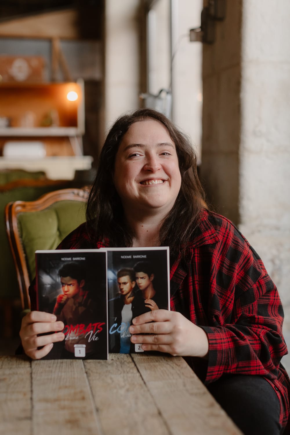 Noémie Barronie souriante, tenant ses romans dans les mains.
