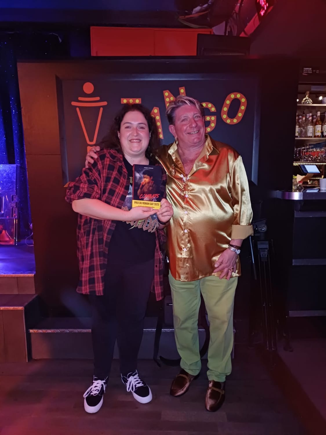 Noémie Barronie posant lors d’un événement, aux côtés d’une autre personne, dans une ambiance de soirée.