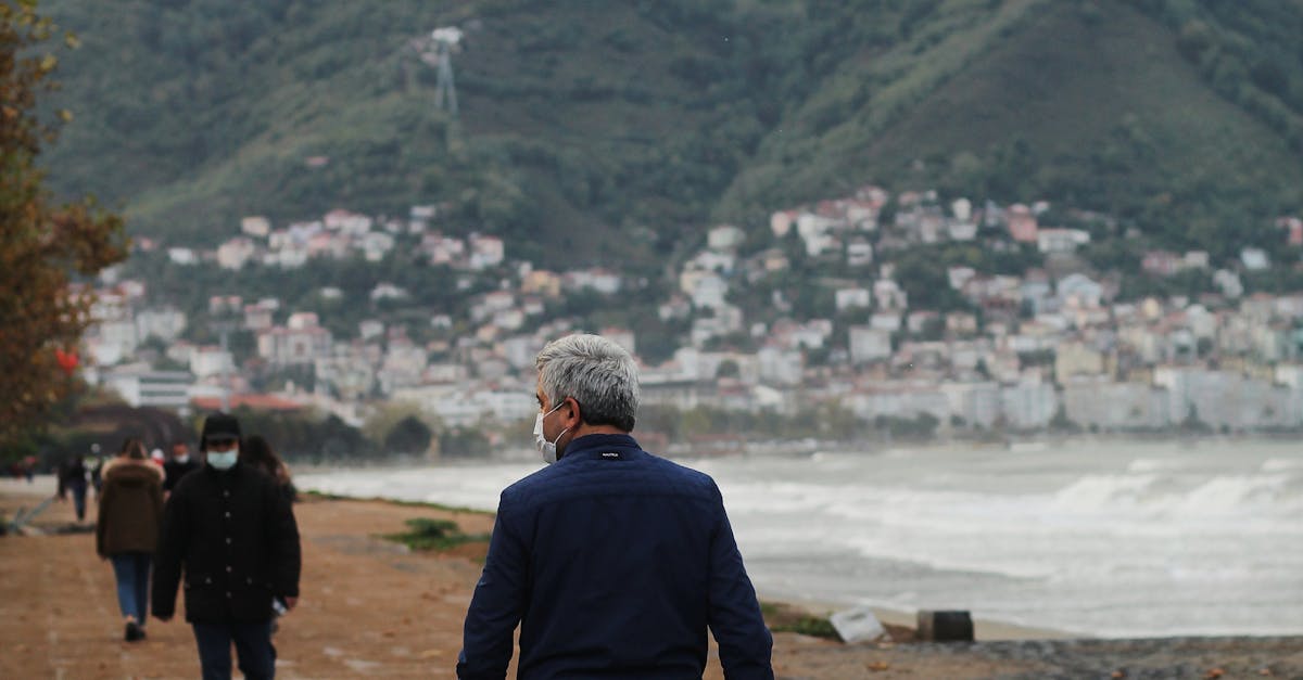 Unrecognizable man wearing mask and child walking together on embankment	