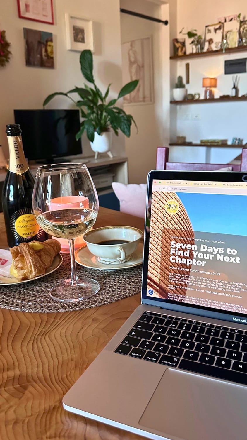 A chilled glass of Prosecco catching the spring sunlight in a Florentine attic office, celebrating a midlife business launch.