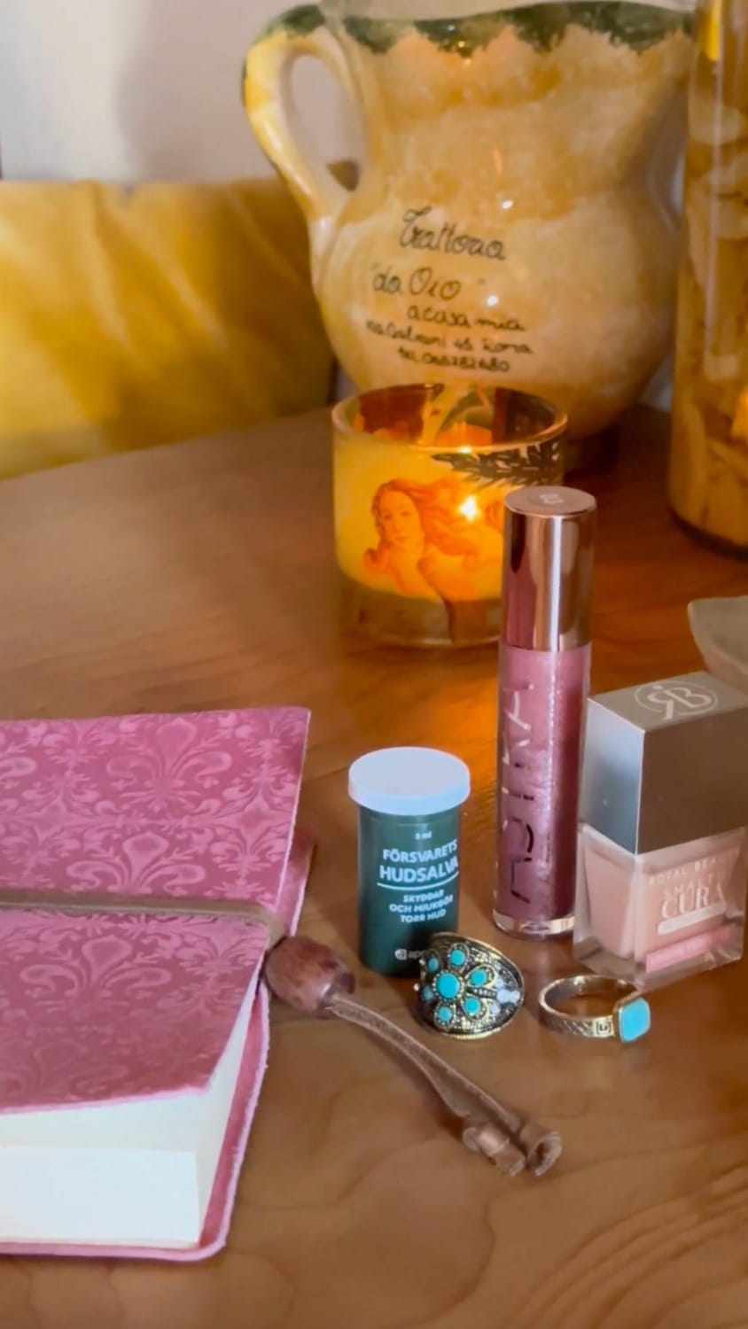A Venus candle, a lipstick and a vintage notebook on a wooden desk in Florence, representing the creative process of midlife reinvention.